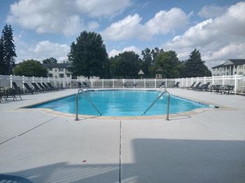 a resort style pool with deck chairs and a fence around it